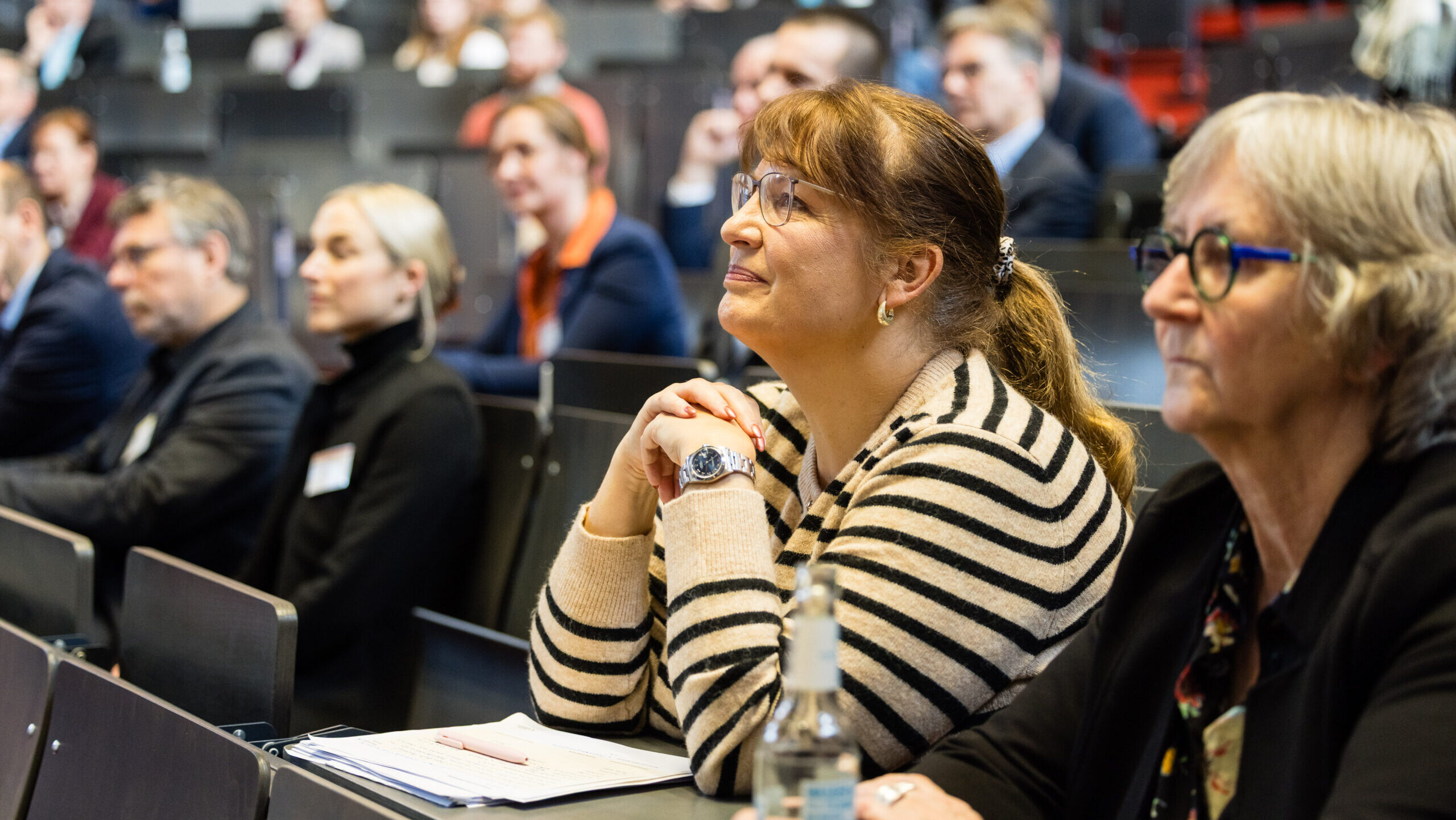 Teilnehmende hören aufmerksam der Podiumsdiskussion zu. 