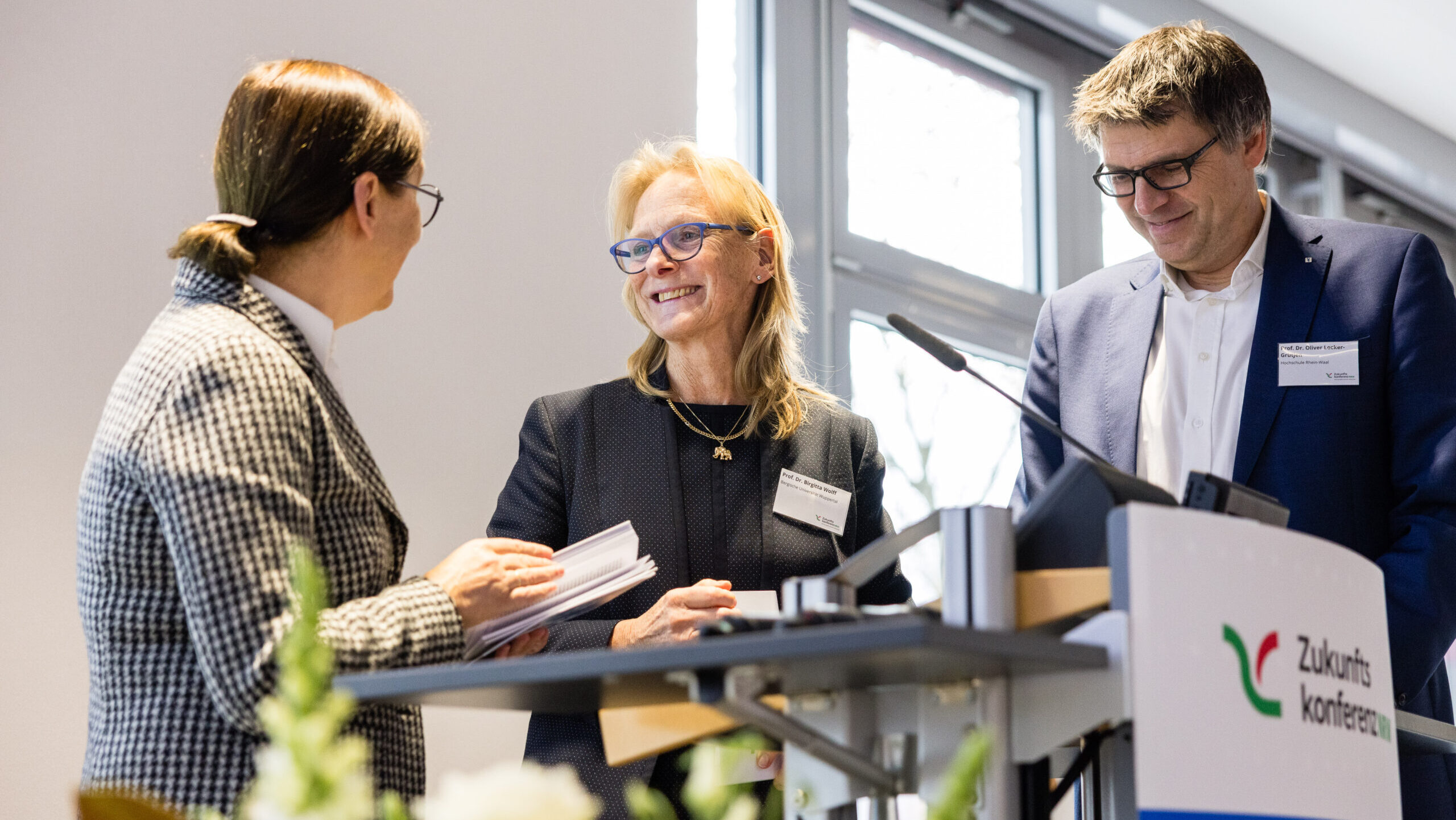 Prof. Barbare Albert, Prof. Brigitta Wolf und Prof. Oliver Locker-Grütjen stehen gemeinsam auf der Bühne. 
