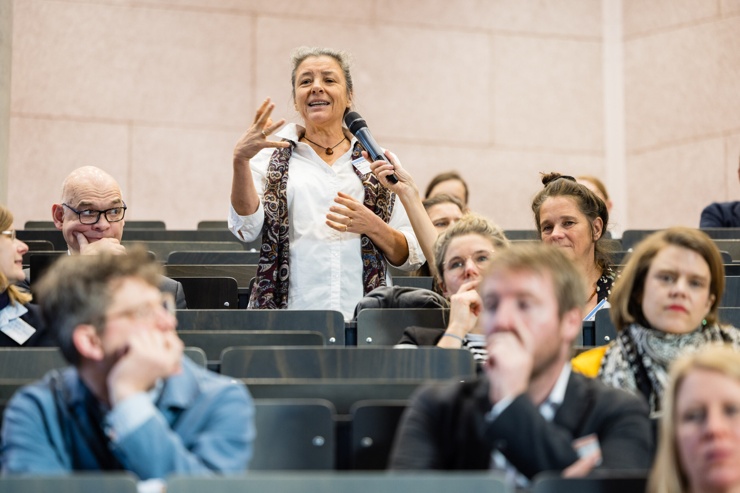 Person aus dem Plenum gibt im Hörsaal einen Wortbeitrag.